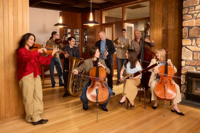 Adelaide Symphony Orchestra musicians posing together with various classical instruments indoors for their concert season program